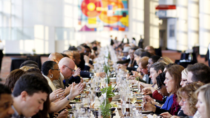 A long dining table with hundreds of people seated