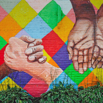 Mural depicting hands of many colors against a bright checkered background.