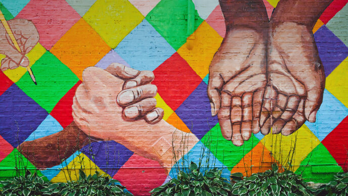 Mural depicting hands of many colors against a bright checkered background.