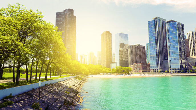 View of the Chicago lakeshore with the sun shining behind Lake Point Tower and the Gold Coast neighborhood||