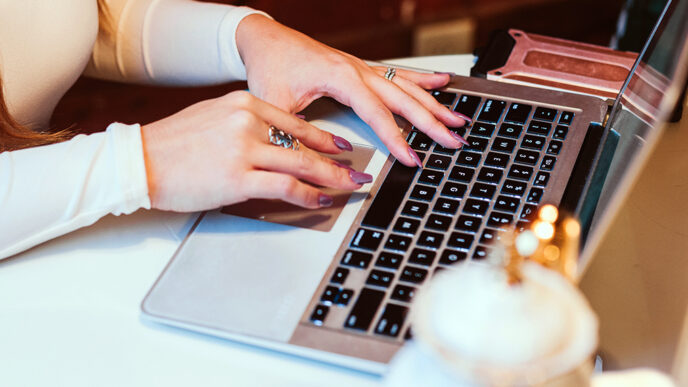 Close-up of a woman's hands typing on a laptop